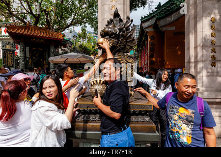 I turisti cinesi Rub la statua del drago per buona fortuna all'entrata di Wong Tai Sin Temple, Hong Kong, Cina Foto Stock