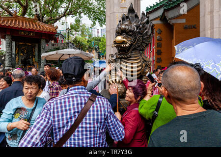 I turisti cinesi Rub la statua del drago per buona fortuna all'entrata di Wong Tai Sin Temple, Hong Kong, Cina Foto Stock