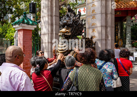 I turisti cinesi Rub la statua del drago per buona fortuna all'entrata di Wong Tai Sin Temple, Hong Kong, Cina Foto Stock