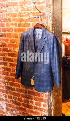 Un blue tweed tuta è appeso un appendiabiti rosso su rosso di un muro di mattoni. Foto Stock