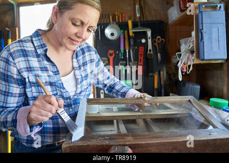 Donna matura Upcycling mobili in officina a casa armadio dipinto Foto Stock