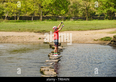 OGMORE DAL MARE, GALLES - Aprile 2019: Persona in abbigliamento ciclo prendendo un selfie immagine su un telefono cellulare mentre in equilibrio su le pietre miliari Foto Stock