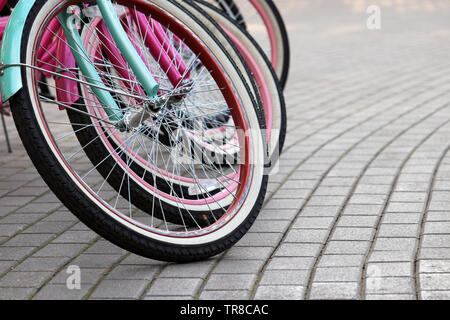 Biciclette su un parcheggio, ruote in una fila su un marciapiede. City bike sistema di noleggio Foto Stock