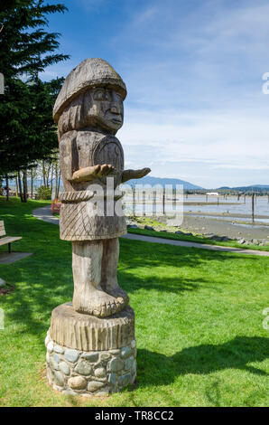 Il Salish totem "accogliente figura' scolpito dal riso alle erbe, Cowichan Bay, l'isola di Vancouver, British Columbia, Canada Foto Stock