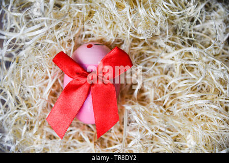 Rosa le uova di pasqua con il red ribbon bow nel nido su sfondo vista superiore Foto Stock