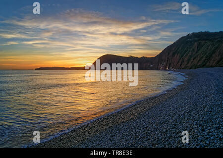 UK,Devon,Sidmouth,Tramonto guardando ad ovest dalla scaletta Jacobs Beach Foto Stock