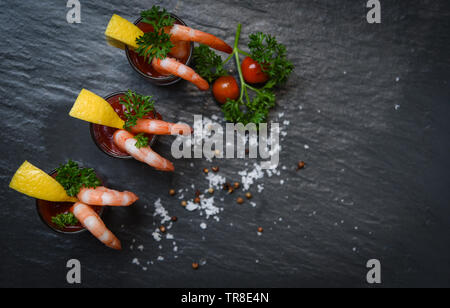 Vetro cocktail di gamberi in salsa di pomodoro / frutti di mare Pesce bollito di gamberi Ketchup di pomodoro e spezie di limone su sfondo scuro vista superiore Foto Stock