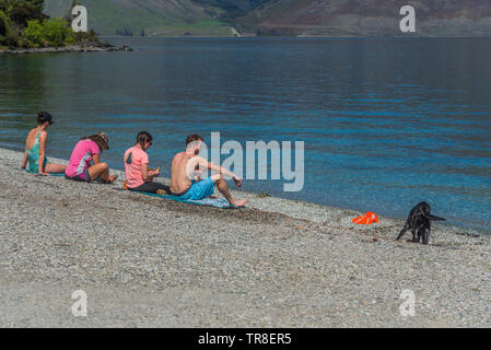 QUEENSTOWN, Nuova Zelanda - 10 ottobre 2018: un gruppo di persone sedersi in riva al lago Wakatipu. Copia spazio per il testo Foto Stock