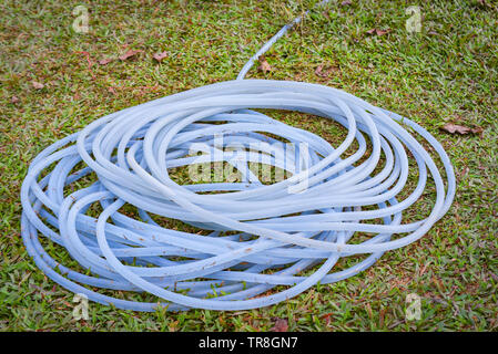 Rotolo di tubo in gomma nel giardino per impianto di irrigazione Foto Stock