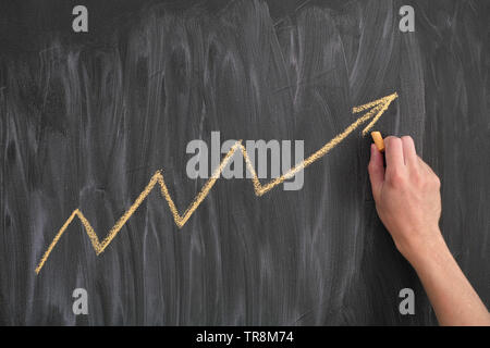 Disegno a mano una freccia gialla che sta in alto. Blackboard sfondo. Il concetto di business. Foto Stock