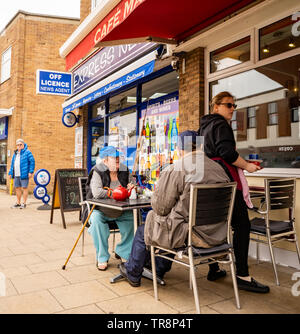 Cromer, Norfolk, Regno Unito. 19 maggio 2019. Una coppia di mezza età seduta al di fuori di una caffetteria in strada alta. Foto Stock