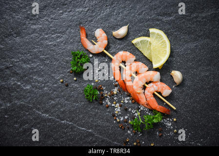 Gamberi in bastoni spiedino di frutti di mare e cotto con erbe e spezie su sfondo scuro Foto Stock