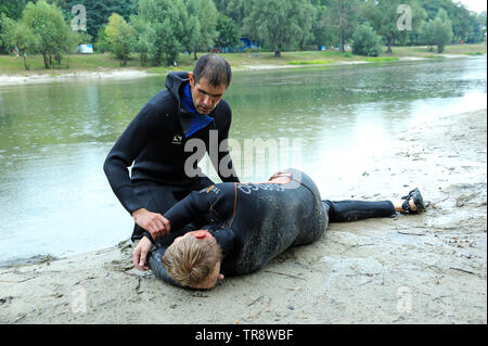 Bagnini che mostra la posizione del corpo di annegamento prima di fare la bocca a bocca rianimazione. Agosto 10,2018. A Kiev, Ucraina Foto Stock
