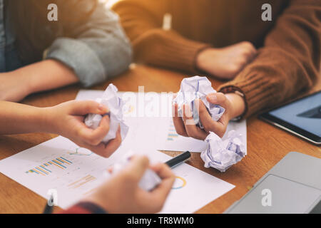 Un imprenditore avvitato in su carta a mano con laptop, tablet e della carta di lavoro sul tavolo in una riunione Foto Stock