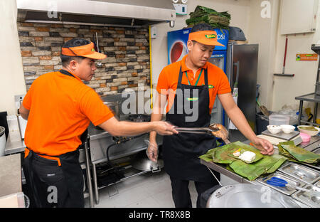 Manila, Filippine - Luglio, 26, 2016: due giovani uomini che serve cibo in un ristorante filippino cucina a Manila Foto Stock