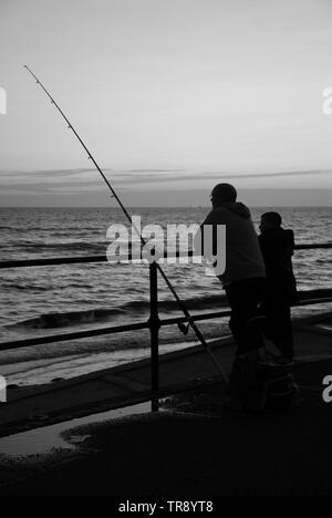 Nonno & nipote pesca al largo della parete del mare a Crosby beach Liverpool. Foto Stock