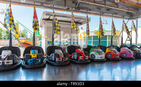 Bergamo, Italia - Maggio 2019: Piccoli paraurti colorati automobili per bambini con le bandiere in un parco italiano durante una fiera. Molla, bella giornata, vibranti. Foto Stock