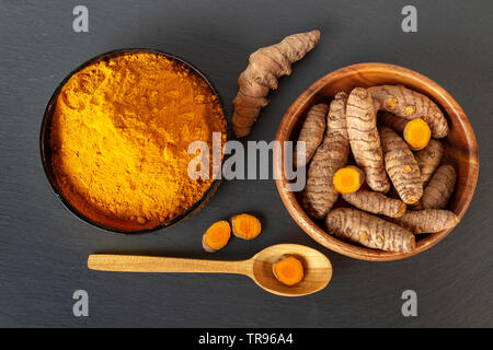 Curcuma radici e polvere sul grigio Sfondo di ardesia, overhead shot Foto Stock