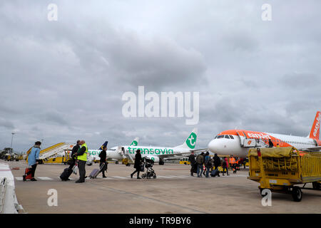 I passeggeri con riporto su bagagli all'aeroporto di Lisbona a piedi attraverso l'asfalto a bordo di un aereo Easyjet per volare a Londra England Regno Unito 2019 KATHY DEWITT Foto Stock