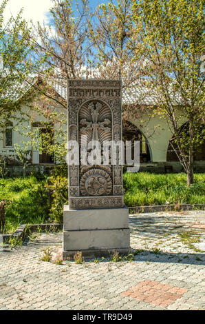 Khachkar di pietra grigia con motivi etnici nel cortile della chiesa dei Santi Martiri nel villaggio di Teghenik in Armenia Foto Stock