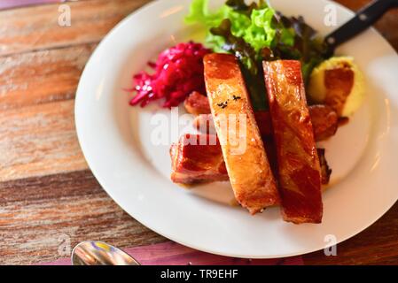 Primo piano di arrosto di Costolette di Maiale con Insalata sul tavolo rustico Foto Stock