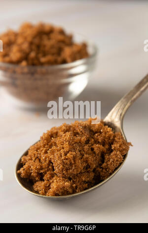 Lo zucchero di canna nel cucchiaio di metallo sul luminoso, Sfondo marmo con copia spazio. Ingrediente di dessert, zucchero di tossicodipendenti, spazio di copia Foto Stock