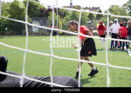 Una giovane ragazza nera prende un colpo a obiettivo durante una sessione di formazione su un passo astroturf Foto Stock