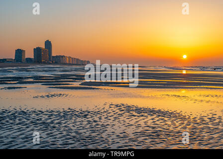 Tramonto lungo la spiaggia del Mare del Nord di Ostenda con il suo skyline urbano e unsharp foreground, Fiandre Occidentali, Belgio. Foto Stock