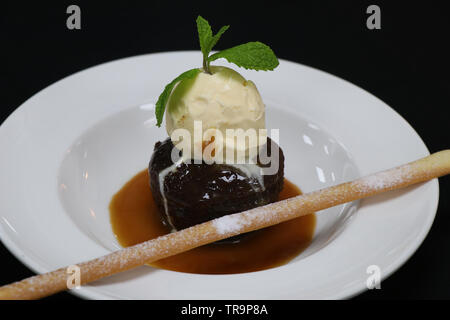Sticky toffee pudding con gelato alla vaniglia e salsa di caramello Foto Stock