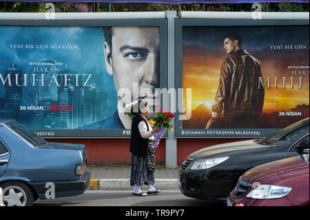 Gypsy le donne che vendono fiori sotto outdoor cartelloni pubblicitari per le strade di Istanbul, Turchia Foto Stock