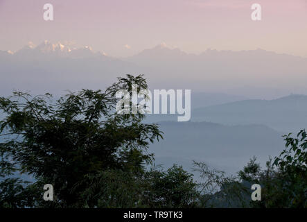 Colline, valli e cime innevate delle montagne dell Himalaya nella nebbia mattutina, stagliano da alberi e visti da Dhulikhel, Nepal Foto Stock