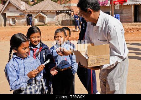 I bambini a scuola uniforme di accettazione di dono del nuovo spazzolino da denti da Global sorride la carità, Samata Scuola di bambù, Bhaktapur, Valle di Kathmandu, Nepal Foto Stock