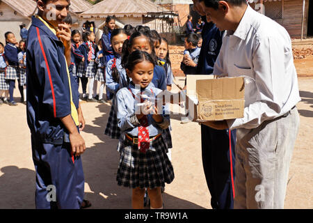 I bambini a scuola uniforme di accettazione di dono del nuovo spazzolino da denti da Global sorride la carità, Samata Scuola di bambù, Bhaktapur, Valle di Kathmandu, Nepal Foto Stock