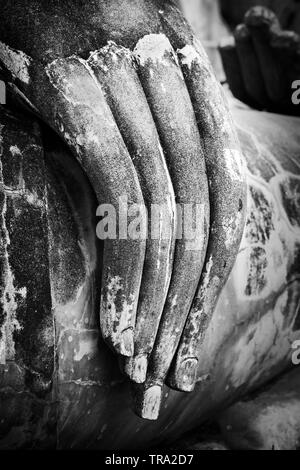 Foto in bianco e nero di un Buddha seduto solo a mano con antiche rocce dita tagliate nella meditazione pongono al Sukhothai Historical Park nel nord della Thailandia Foto Stock