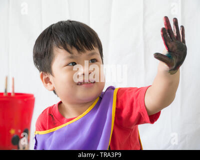 Asian carino boy tenendo premuto il dito sporco e sorridente con felice, Foto Stock