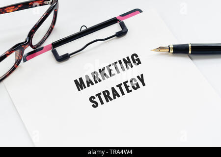 Il concetto di business, appunti con la parola strategia di marketing, penna e occhiali su sfondo bianco Foto Stock