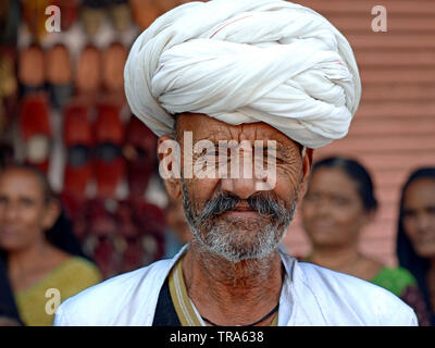 Anziani di Rajasthani indiano Rabari patriarca della famiglia comporta per la fotocamera nella parte anteriore del suo entourage femminile. Foto Stock