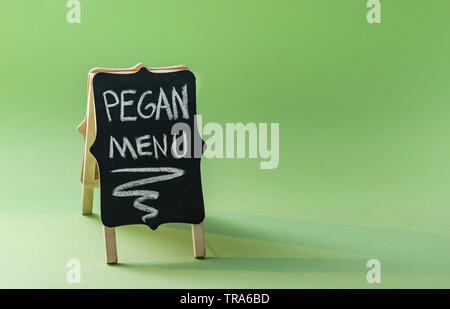 Lavagna con il testo "Menu Pegan' su sfondo verde con copia spazio. Paleo plus concetto vegan. Pegan dieta. Foto Stock