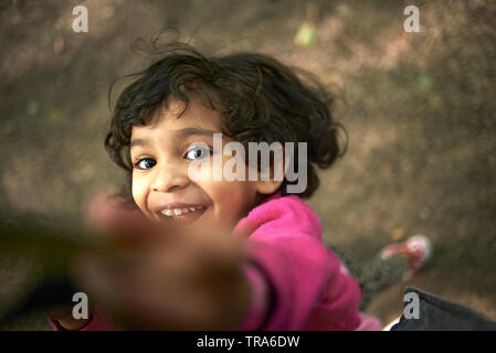 POV di un padre tenendo la sua cute giovane figlia per mano e a far oscillare la sua felicemente intorno Foto Stock