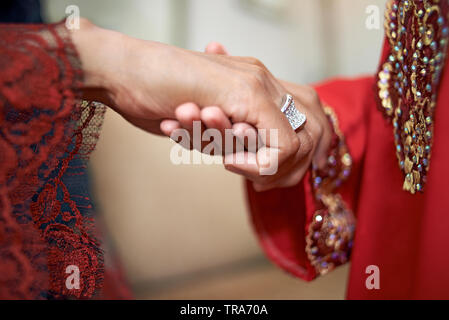 Close up di una madre tenendo la figlia della mano che sta per chiedere il suo perdono e una tradizione nella cultura Malese. Il bacio della mano Foto Stock