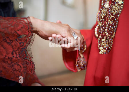 Close up di una madre tenendo la figlia della mano che sta per chiedere il suo perdono e una tradizione nella cultura Malese. Il bacio della mano Foto Stock