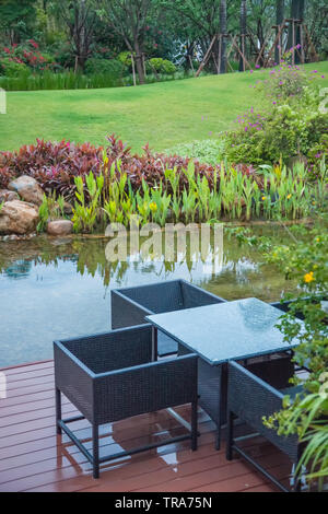 Classic rattan Sedie e tavolo sul balcone di legno accanto al piccolo lago in una pianta verde giardino,Fujian,Cina Foto Stock