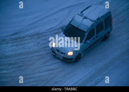 Trasporto, stagione invernale. Movimento auto coperto di neve dopo la bufera di neve e strada. Vista di inverno, la neve sulla strada di città con i fiocchi di neve. Foto Stock