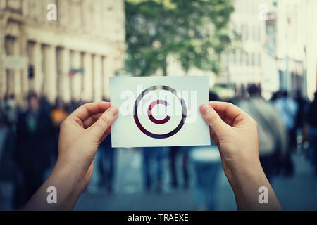 Tenere le mani di carta con il simbolo di copyright. Giuridica Internazionale di diritti di proprietà intellettuale segno, la tutela del brevetto. Il copyleft licenza di marchio. Creazione Foto Stock