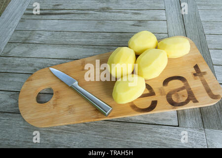 Patate sbucciate e tagliate a fette le patatine fritte su una tavola di legno e un coltello affilato Foto Stock