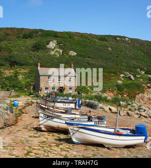 Tipico cottage Cornish costruito sulla banchina a Penberth Cove sulla Penwith Peninsula nella Cornovaglia occidentale, Inghilterra, Regno Unito con barche da pesca in primo piano. Foto Stock