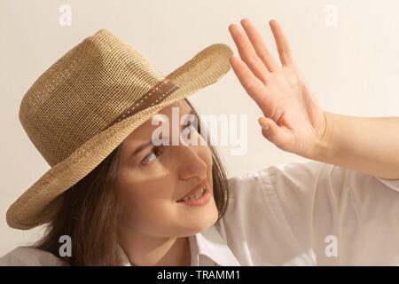 Felice giovane donna nel cappello sotto la luce del sole guardando il sole sorride Foto Stock