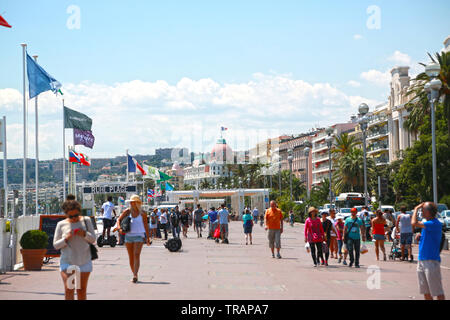 La gente a piedi lungo la passeggiata di Nizza, godendo di una splendida giornata estiva Foto Stock