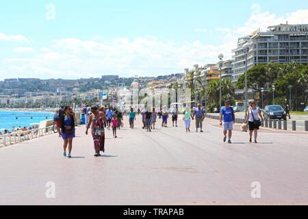 La gente a piedi lungo la passeggiata di Nizza, godendo di una splendida giornata estiva Foto Stock