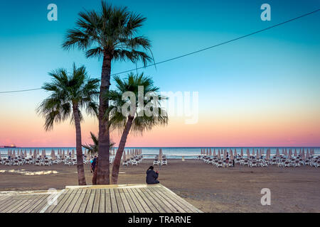 Palme e lettini presso la spiaggia sabbiosa di Larnaca, Cipro Foto Stock